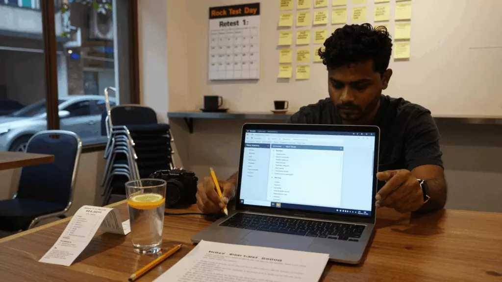 IELTS ছাত্র একটি স্টপওয়াচ এবং নোট সহ একটি সময়মতো মক টেস্ট পর্যালোচনা করছে