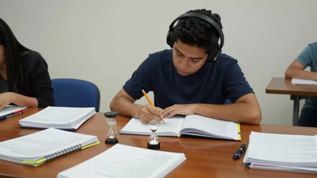 Estudiante ejecuta una prueba de práctica de IELTS con notas, auriculares y un temporizador