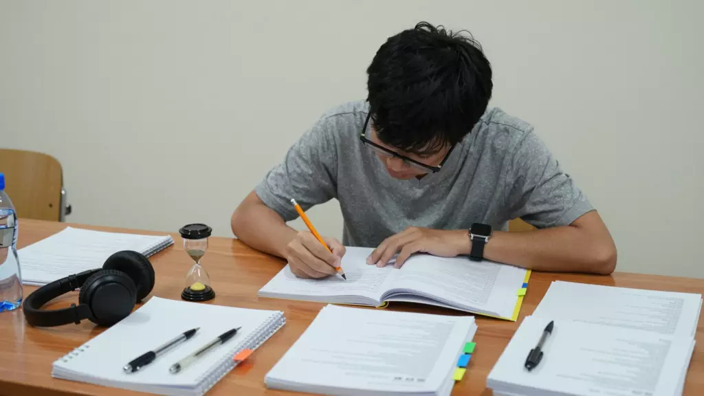 นักเรียนที่ทำแบบทดสอบฝึกหัด IELTS พร้อมโน้ต หูฟัง และ timer